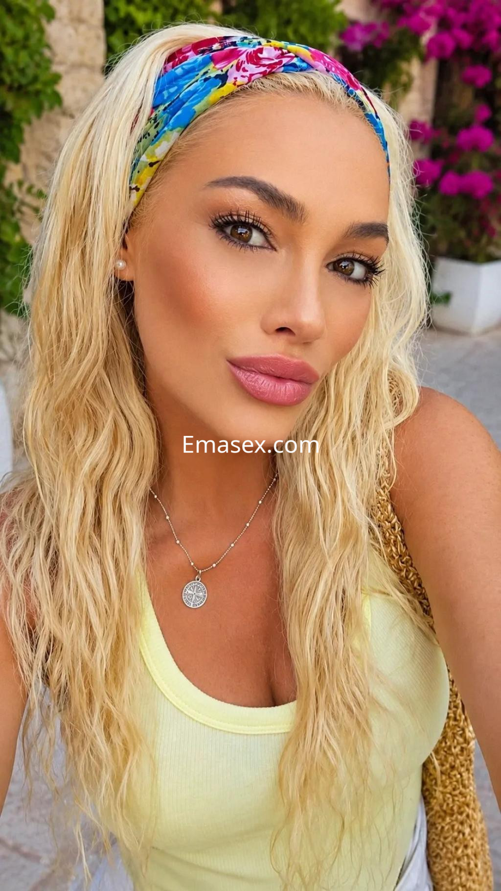 Escort en Palma de Mallorca con cabello rubio y ondulado, usando una blusa amarilla y un pañuelo colorido.