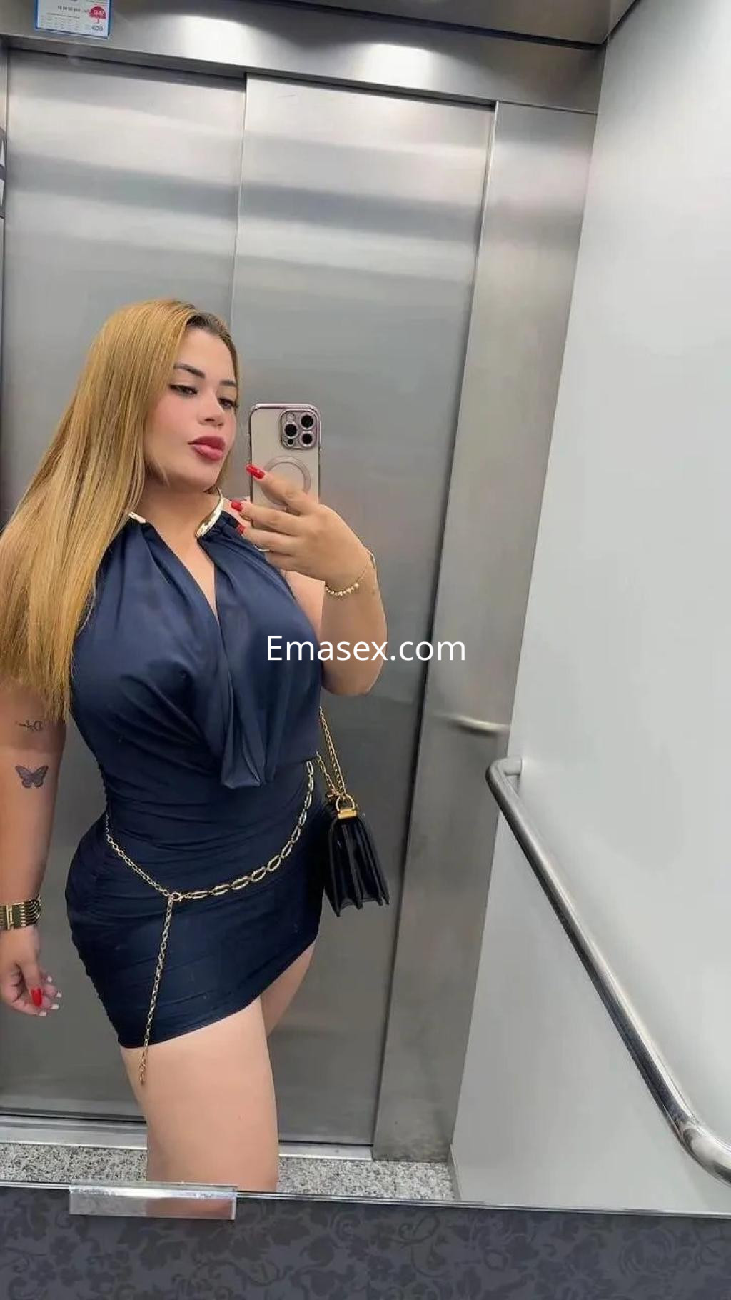 Escort en Madrid con cabello largo y rubio, vistiendo un vestido azul ajustado y posando en un ascensor.