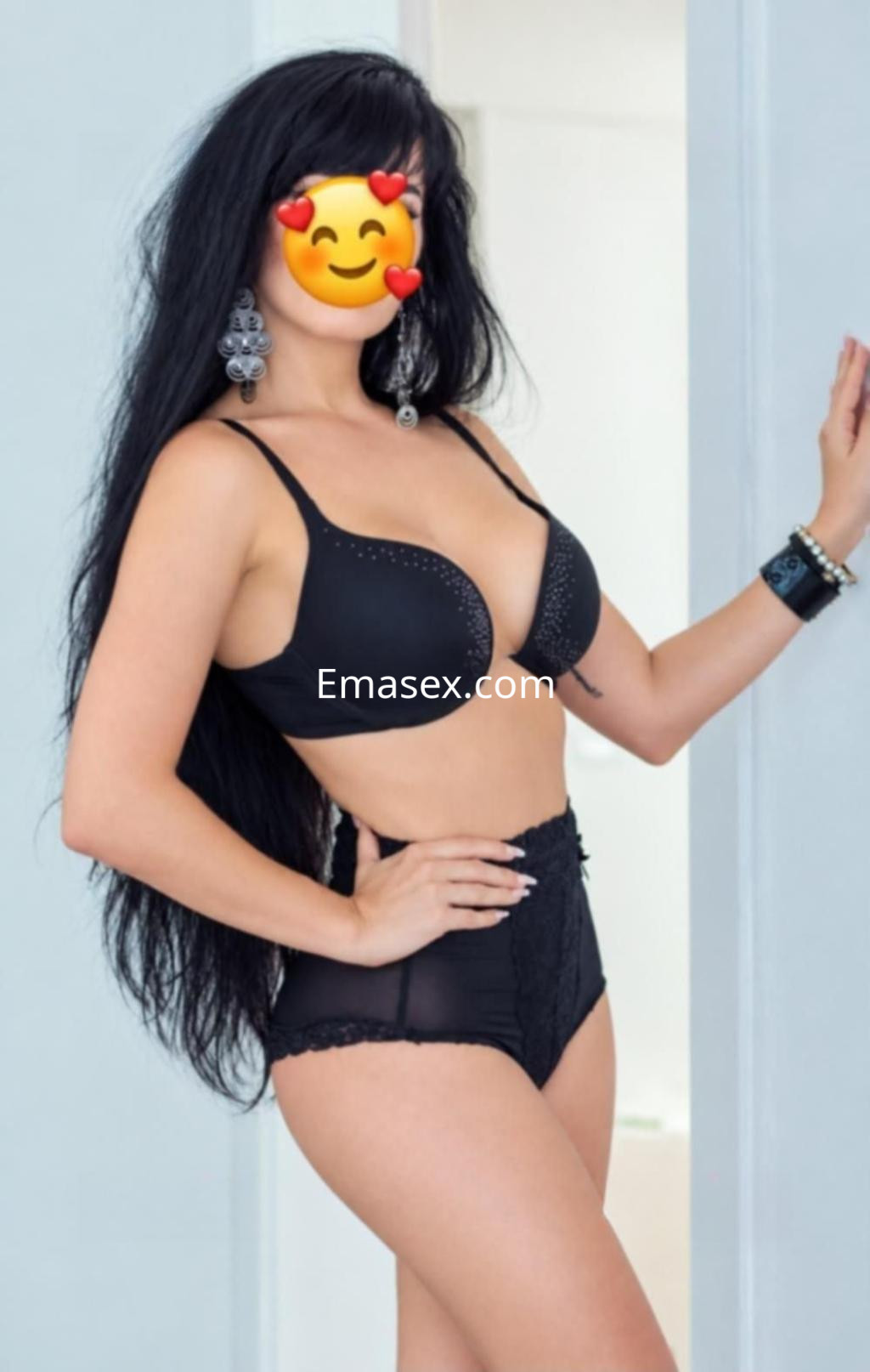 Escort en Lugo con cabello largo y oscuro, luciendo un conjunto de lencería negra y pendientes grandes.