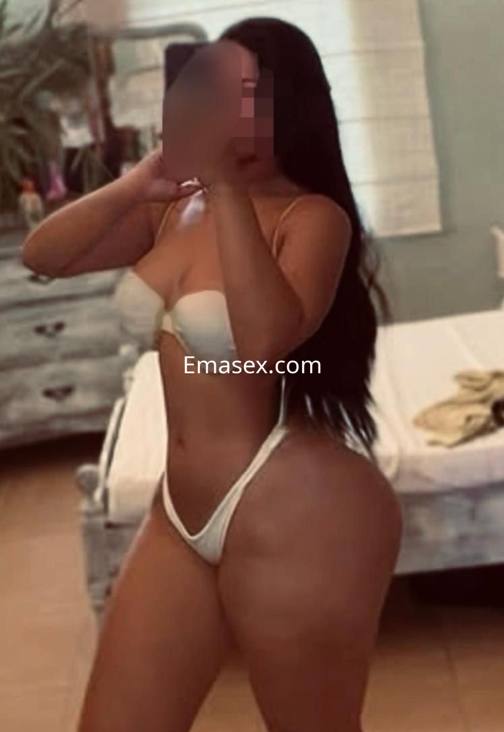 Escort en Sevilla mostrando su figura en una habitación, luciendo un sujetador blanco y una tanga a juego.