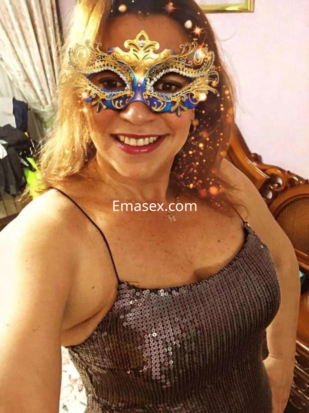 La puta viste un vestido brillante y lleva una máscara decorativa, sonriendo en un entorno acogedor de Madrid.