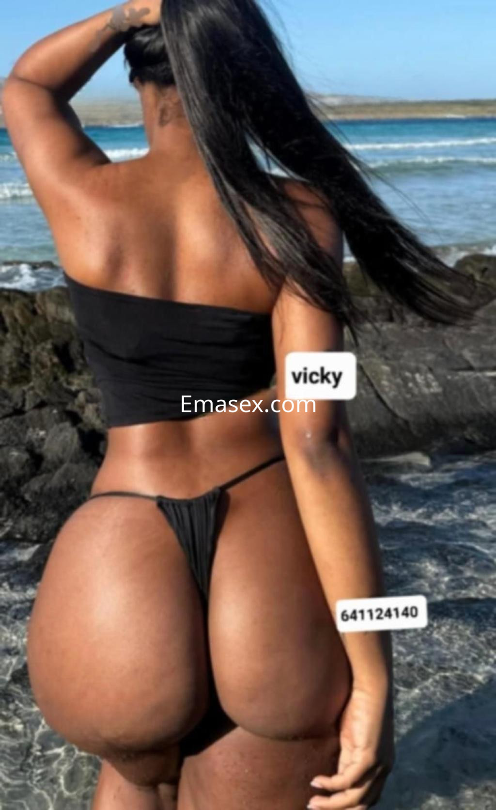 Puta de cabello largo y lacio, viste un bikini negro y se encuentra de espaldas frente al mar en Cádiz.
