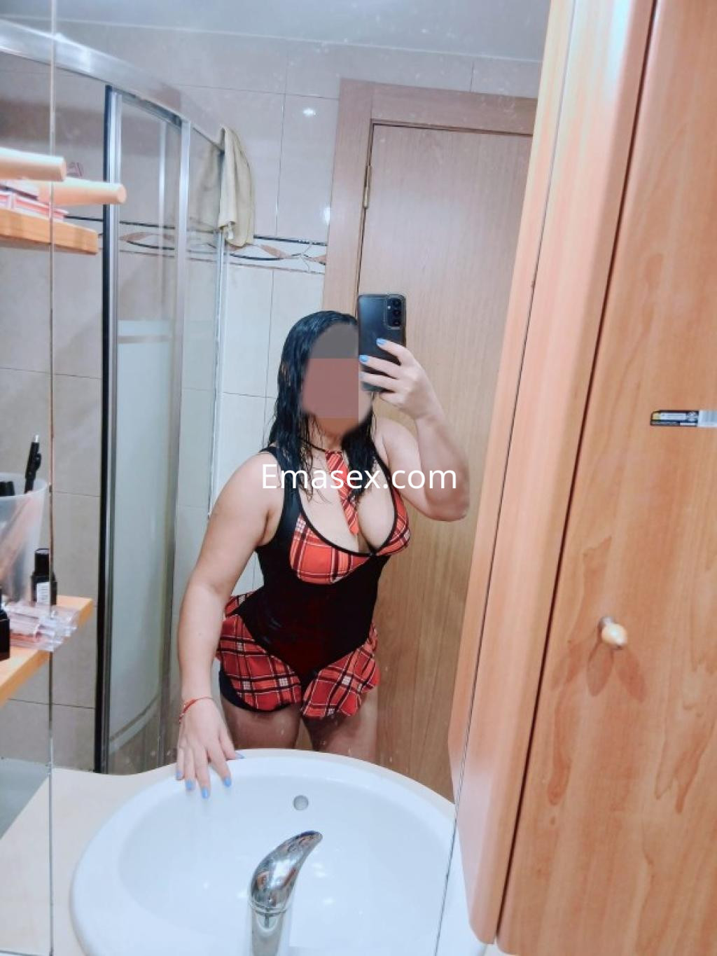 Escort en Lleida, posando frente al espejo con un conjunto de lencería de cuadros y cabello mojado.