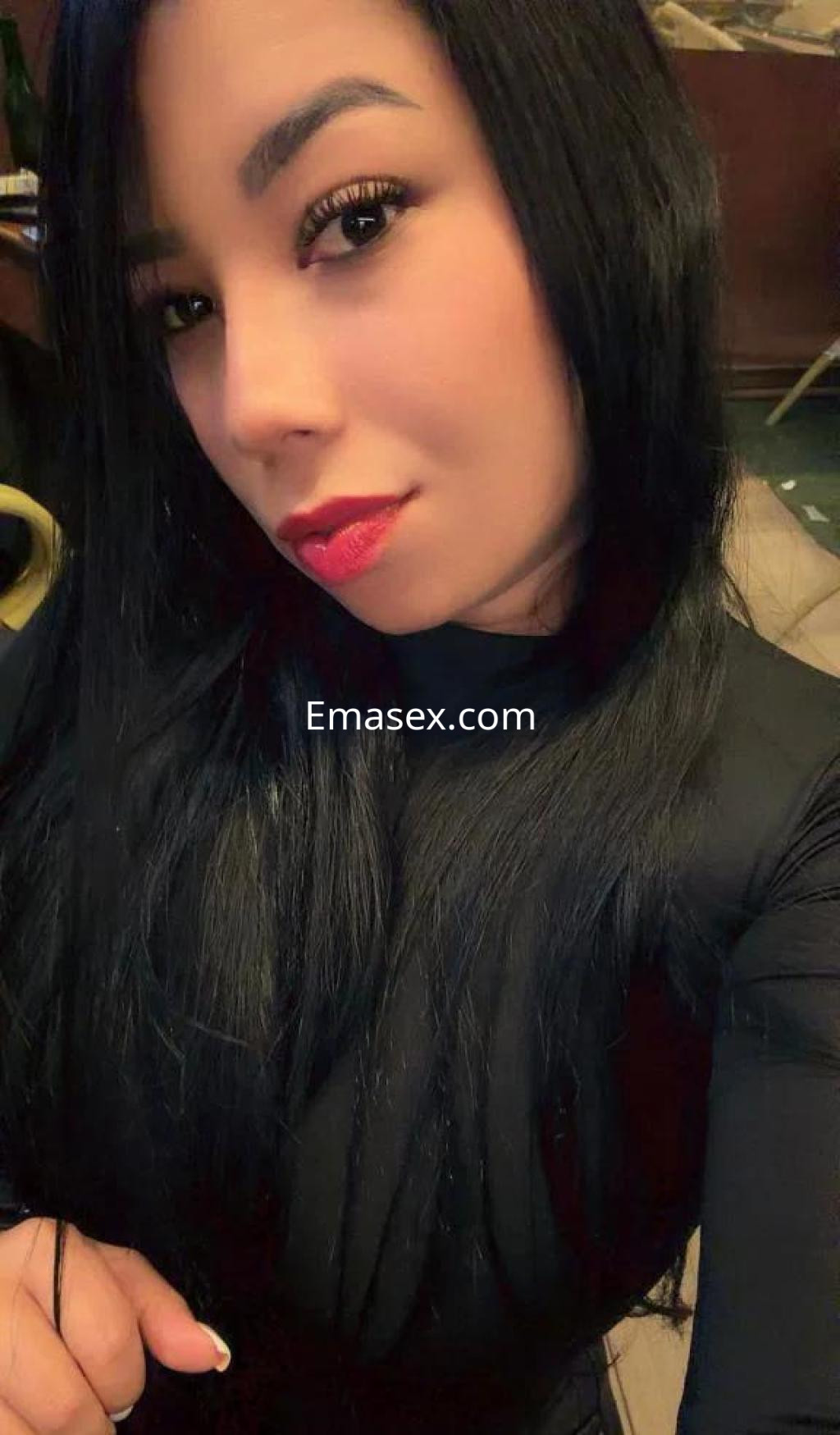 Puta con cabello largo y negro, viste una prenda ajustada y posa con una expresión coqueta en Palma de Mallorca.