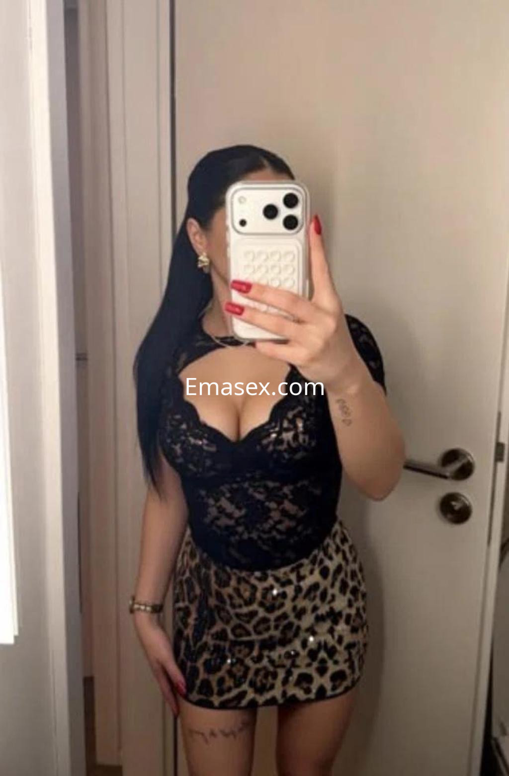 La escort en Lugo posa frente al espejo con un vestido de leopardo y blusa de encaje negra, mostrando su estilo.