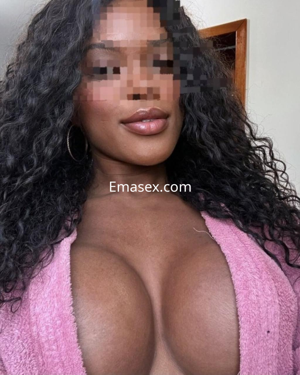 Escort en Girona con cabello rizado y suelto, vistiendo una bata rosa que realza su figura.