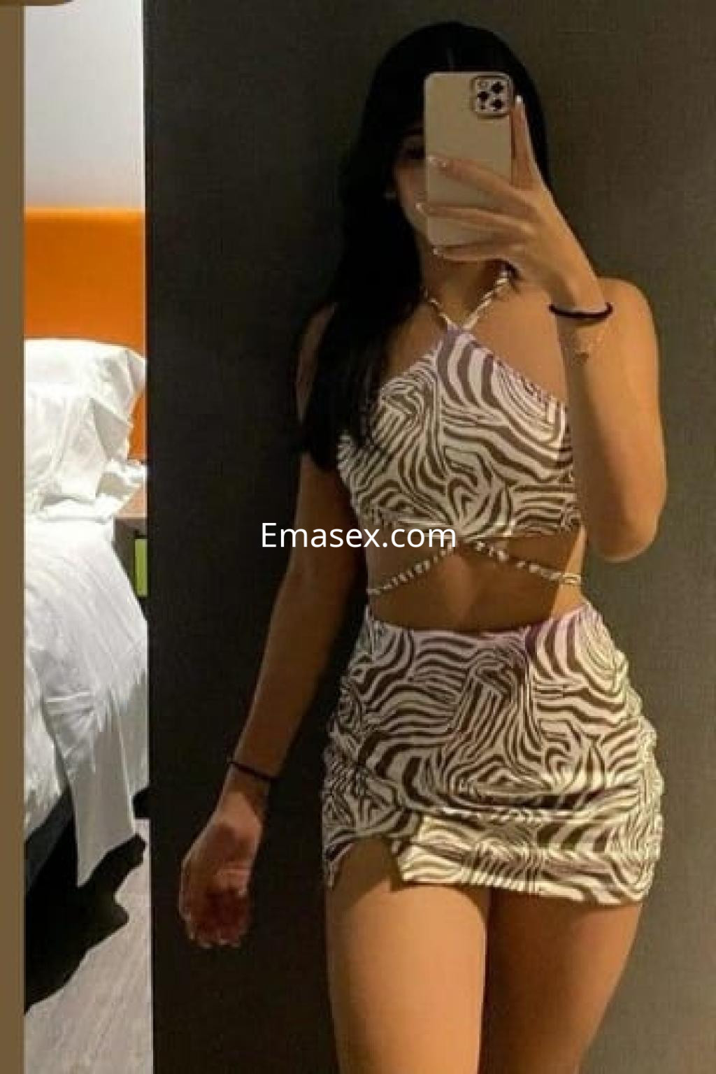 Puta en Burgos con un vestido ajustado de estampado de cebra, posando frente a un espejo en un ambiente interior.