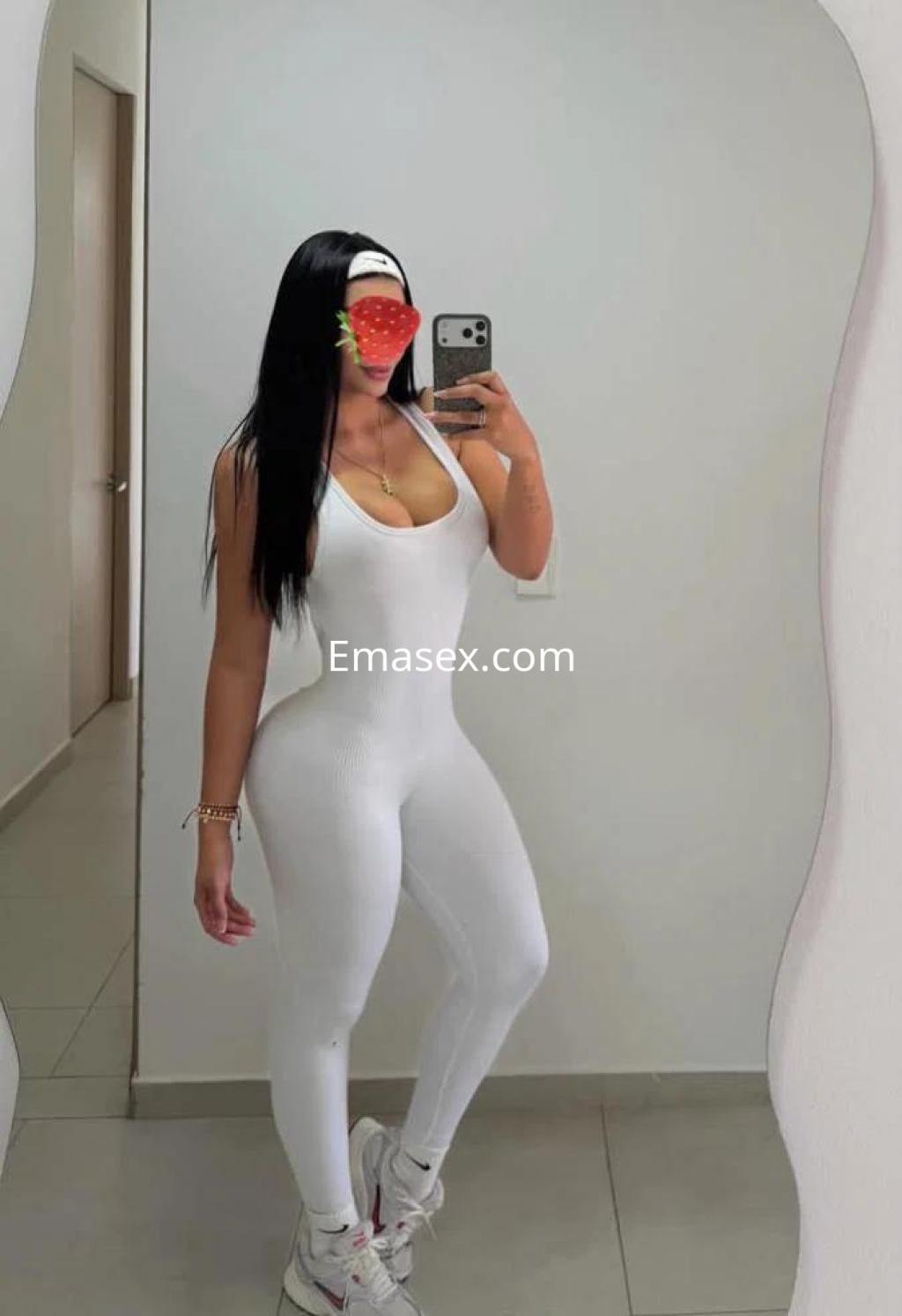 Puta en Palma de Mallorca, posando con un ajustado mono blanco que resalta su figura y cabello largo.