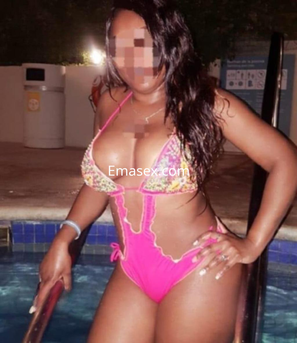 Escort en Sevilla posando junto a una piscina, luciendo un bikini rosa decorado y con cabello largo y oscuro.