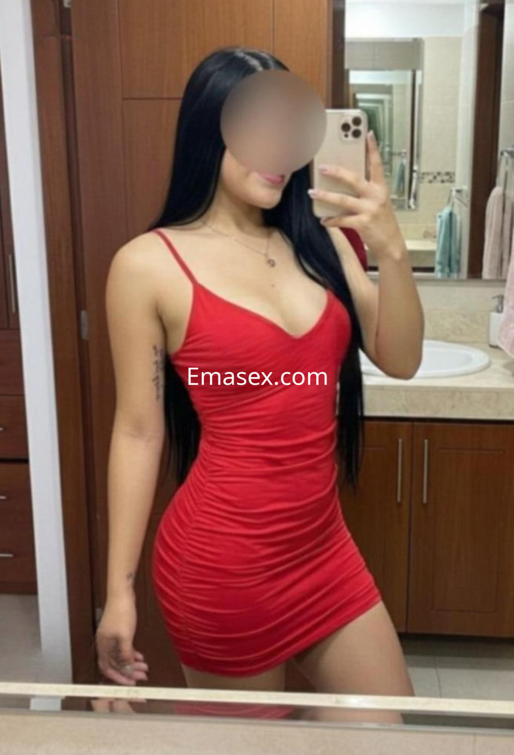 Escort en Madrid con un vestido rojo ajustado y tirantes finos, posando frente a un espejo en un baño.