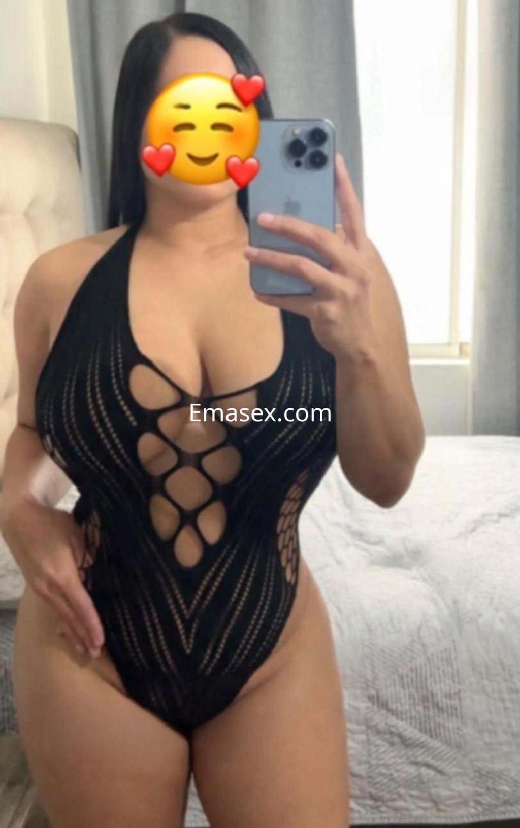Escort en Valladolid vistiendo un body negro con diseño de malla, posando frente a un espejo en un ambiente acogedor.