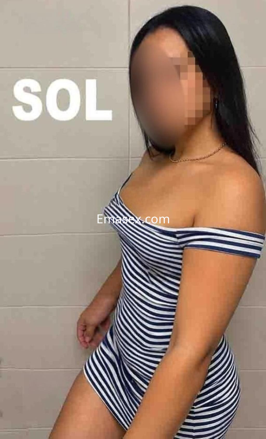 Puta con cabello lacio y oscuro, lleva un vestido de rayas azul y blanco mientras posa en un ambiente interior en Valladolid.