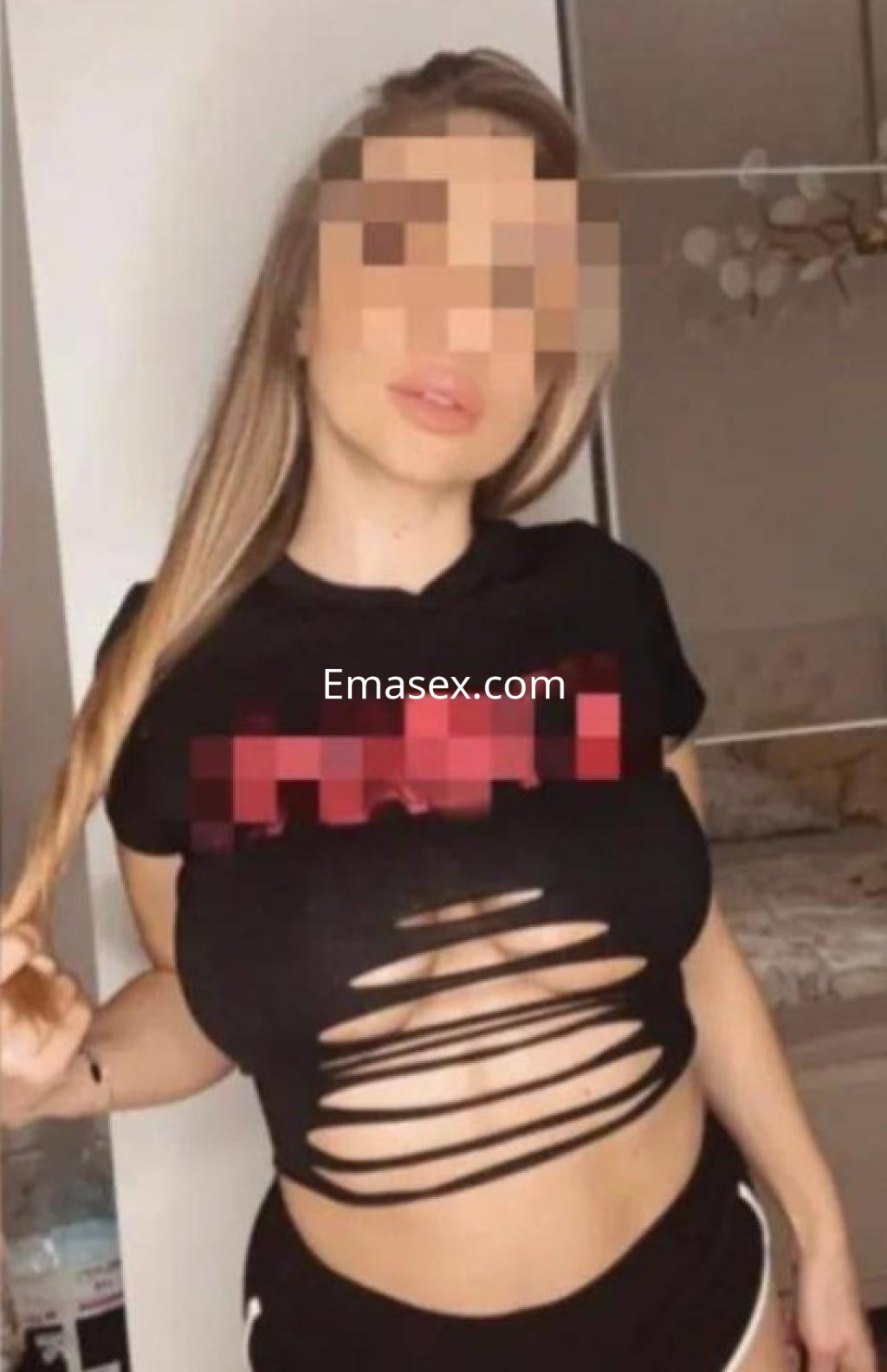 Escort en Valladolid posando con una camiseta negra de cortes y pantalones cortos, mostrando una apariencia atractiva.
