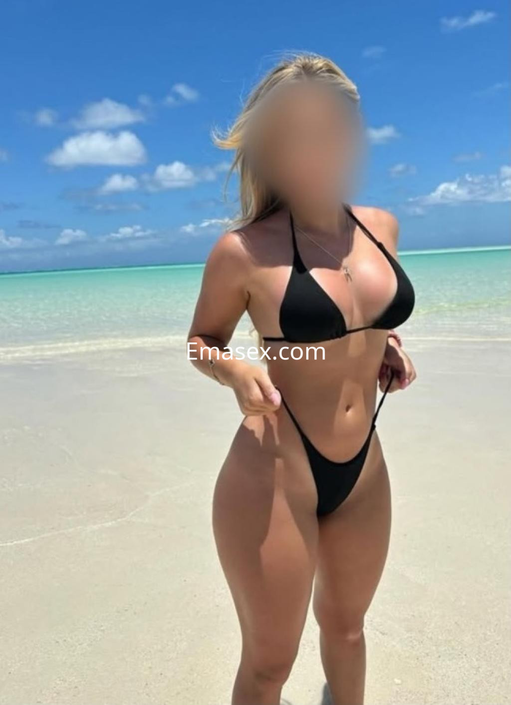 Puta en la playa de Burgos, luciendo un bikini negro que resalta su figura y el entorno marítimo.