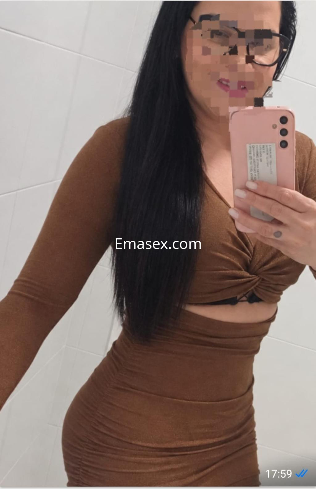 La puta de Pamplona se muestra con un vestido marrón ajustado y de manga larga, sonriendo mientras se toma una selfie.