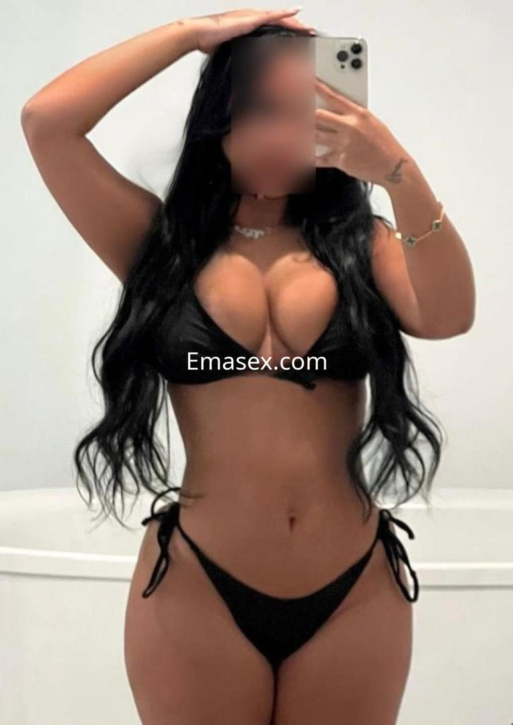 Puta con cabello largo y oscuro, luciendo un bikini negro, posando frente a un espejo en Murcia.