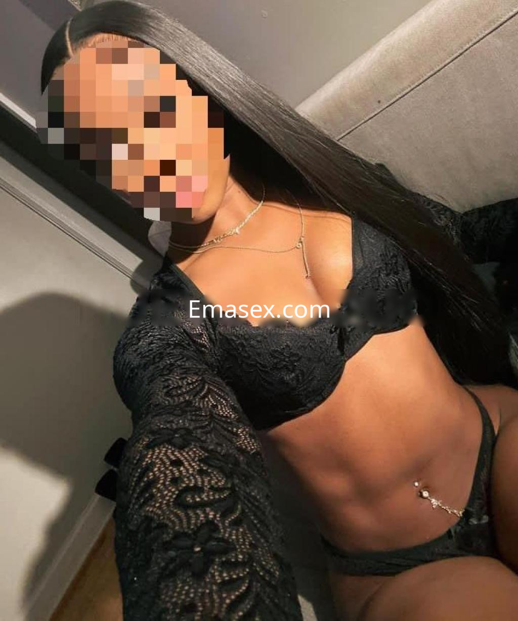 Puta posando en Barcelona, con lencería negra de encaje y una larga melena, mostrando una figura esculpida.