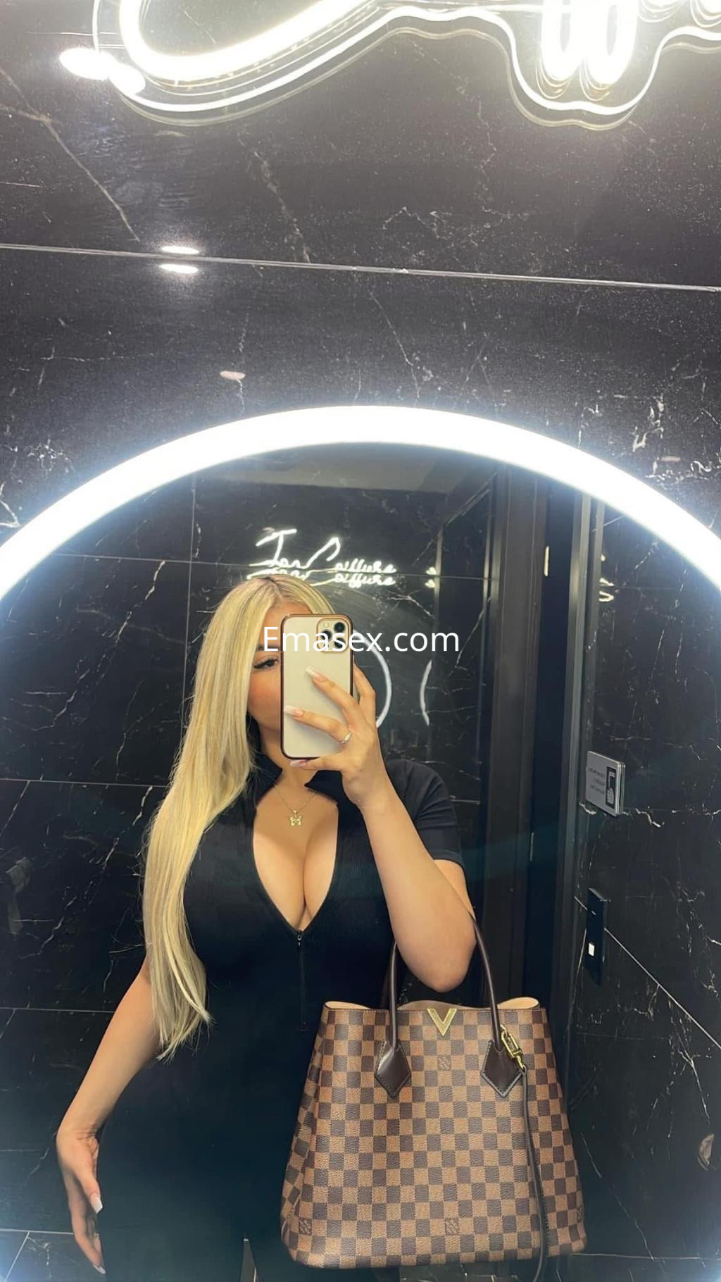 Puta de cabello largo y rubio viste un vestido ajustado mientras se toma una selfie en un baño elegante en Donosti.