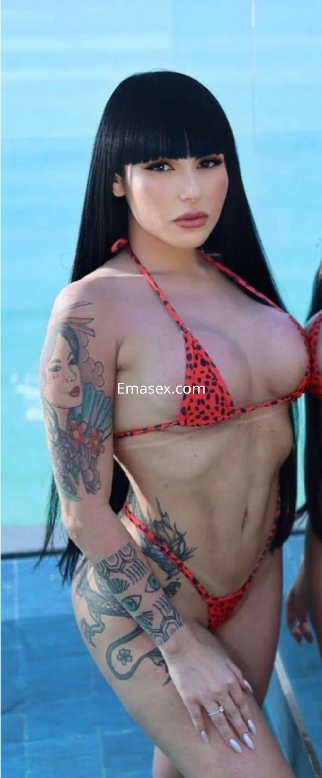 Escort en Bilbao con cabello largo y lacio, vistiendo un bikini rojo con estampado de leopardo y mostrando tatuajes en el brazo.