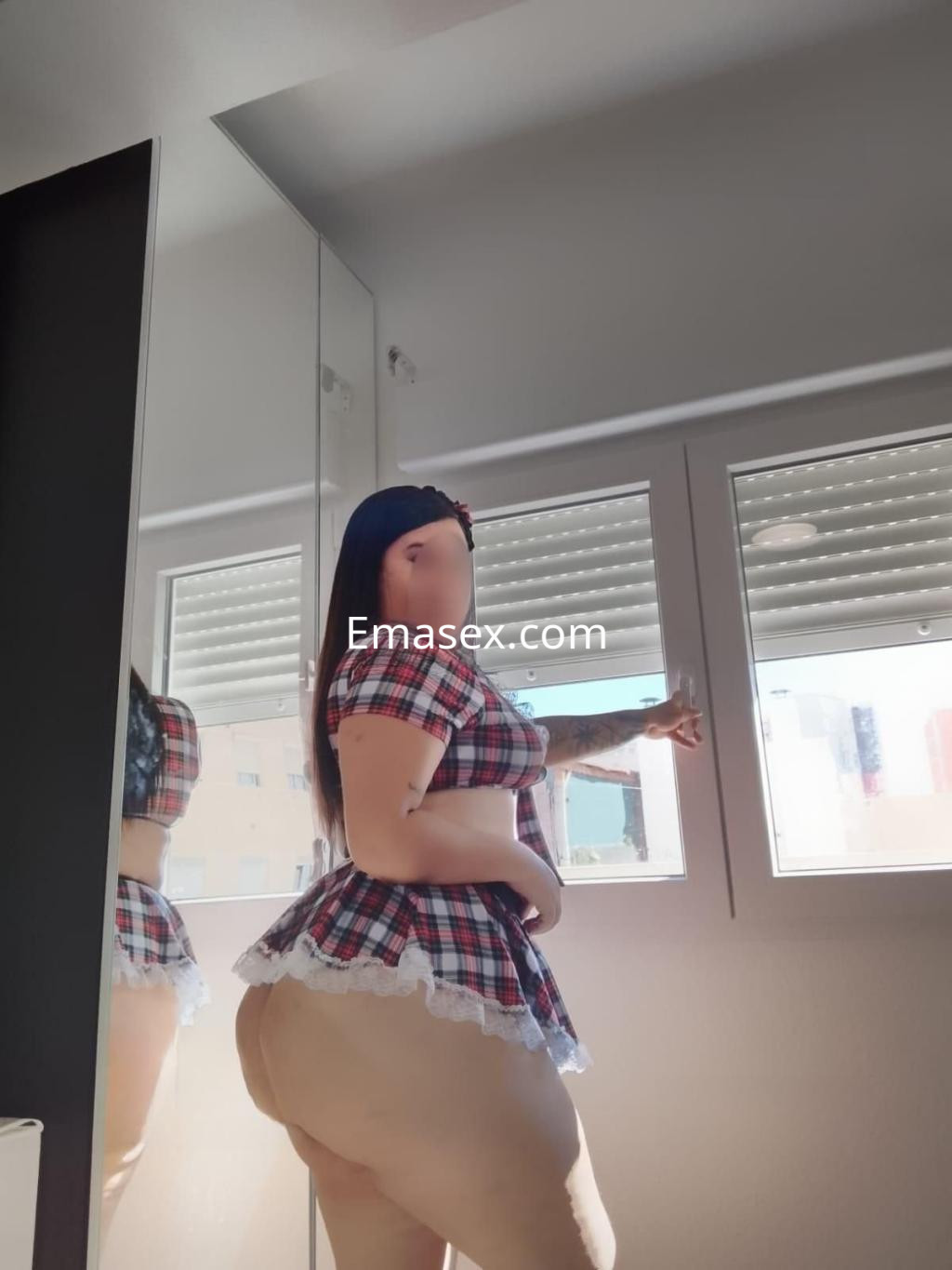 Escort en Tenerife con blusa a cuadros, mostrando un perfil mientras mira por la ventana.