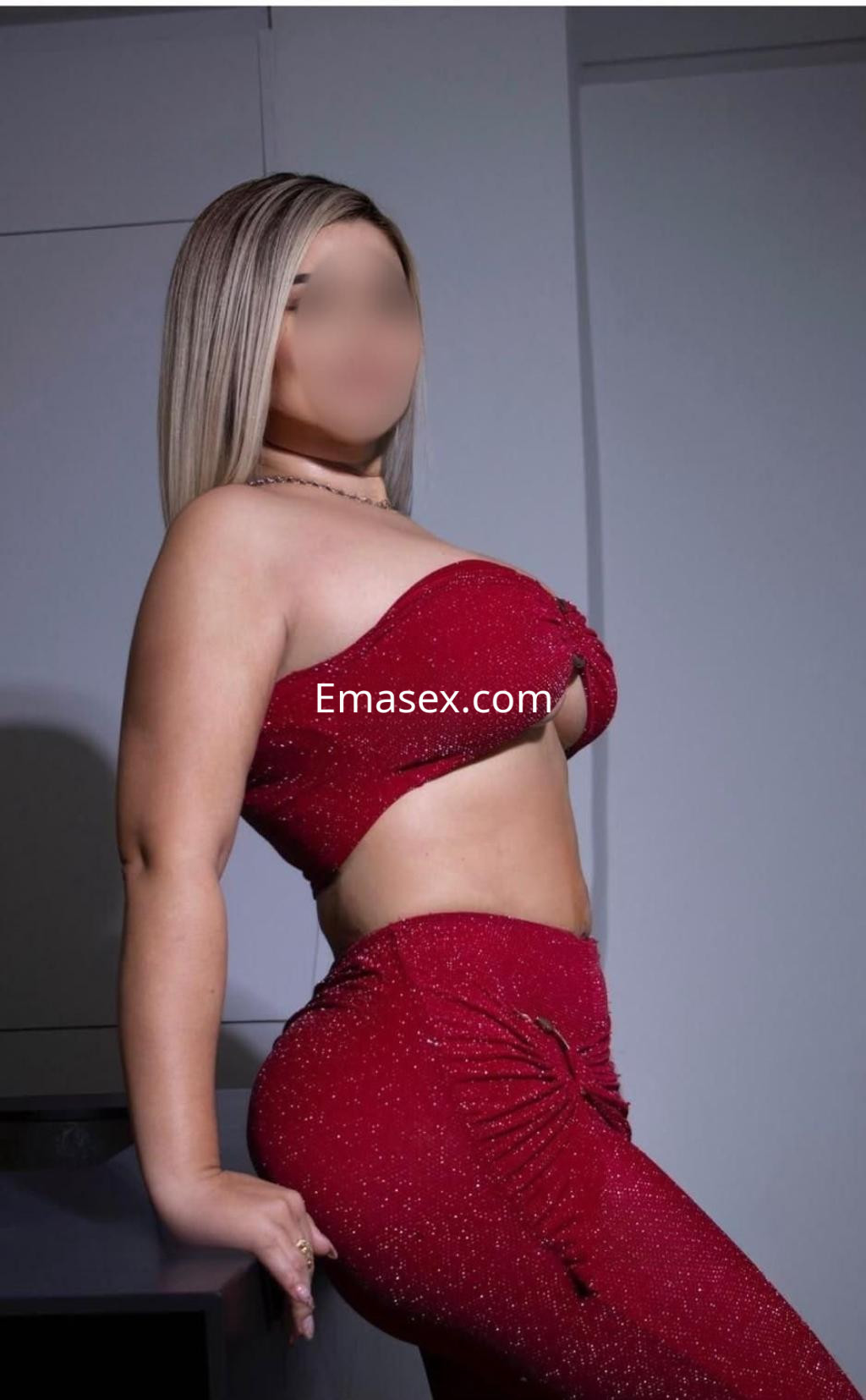 Puta en Tenerife, posa con un top rojo brillante y pantalones ajustados, mostrando una figura esbelta y cabello lacio.