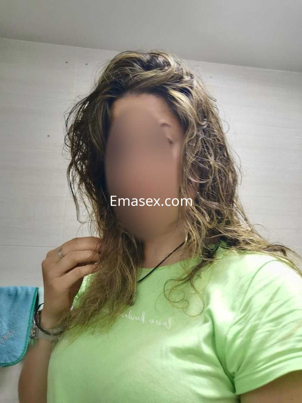Escort en Madrid con cabello rizado y húmedo, vistiendo una camiseta verde en un entorno interior.