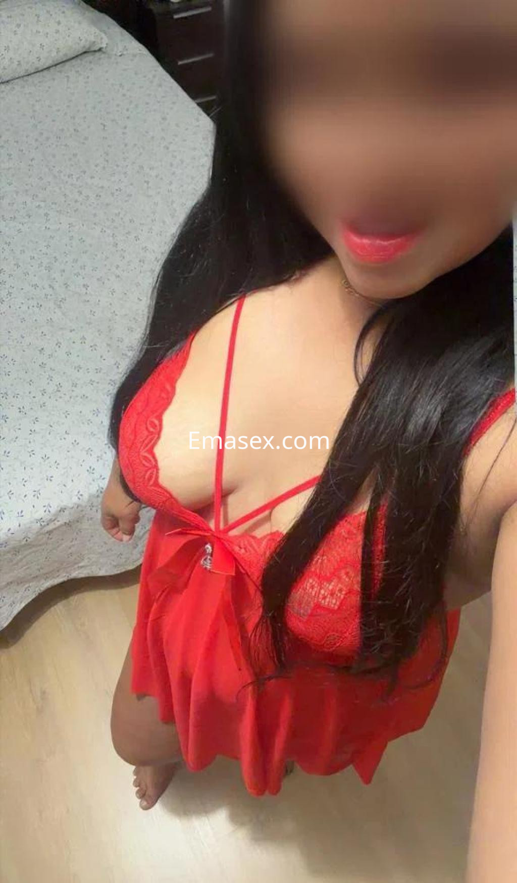 Escort en Valladolid con cabello largo y oscuro, vistiendo un conjunto de lencería roja mientras sonríe.