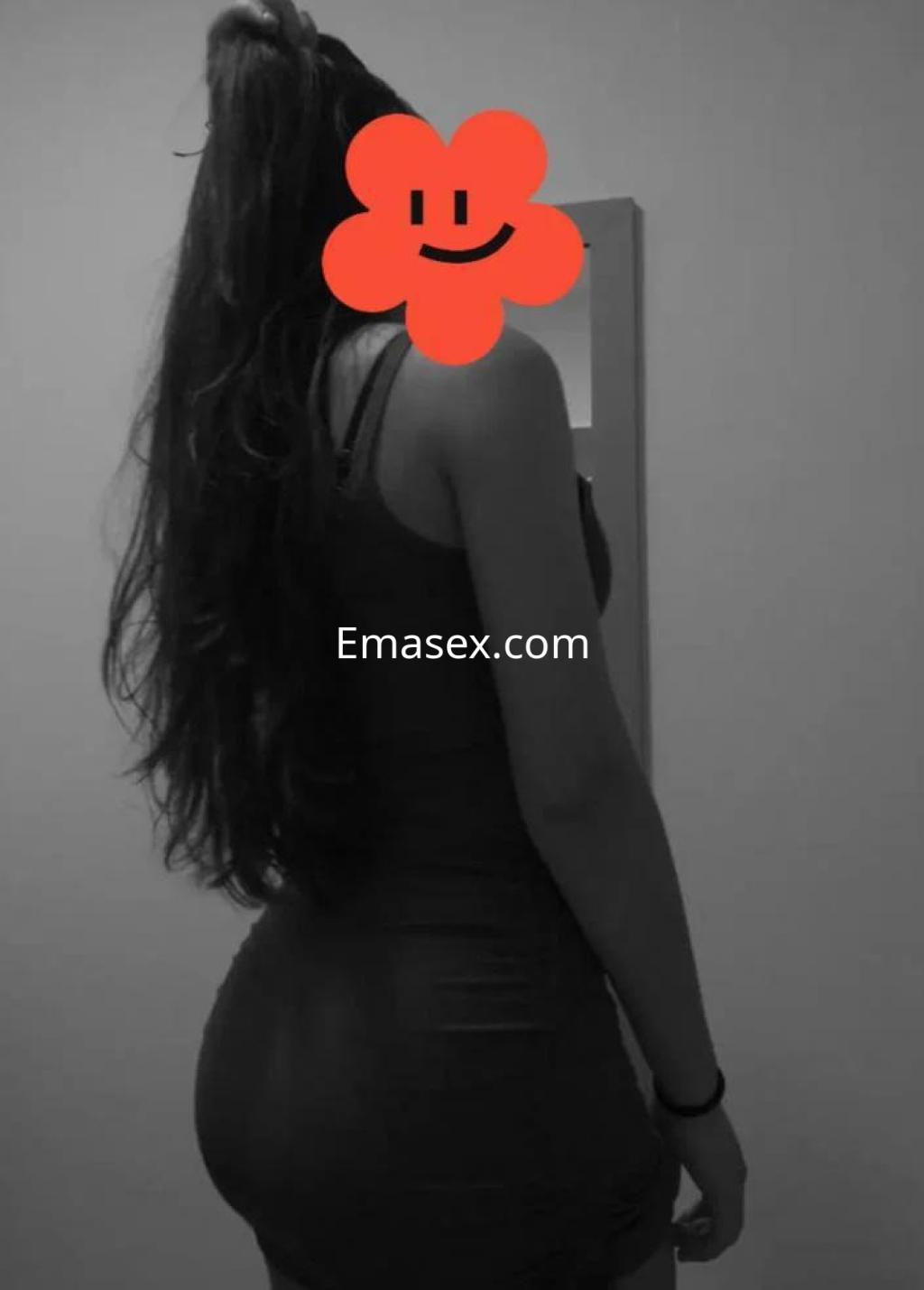 Escort de espaldas en Murcia, luciendo un vestido ajustado y con cabello largo y lacio.