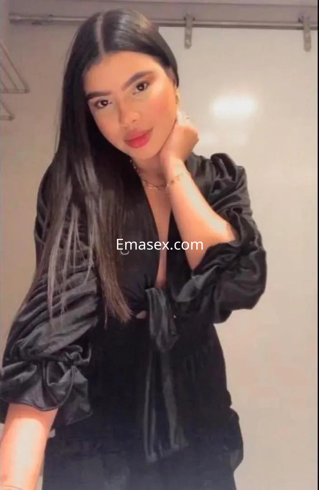 Escort en Vigo con cabello largo y lacio, vistiendo una blusa negra de mangas abullonadas y con un toque elegante.