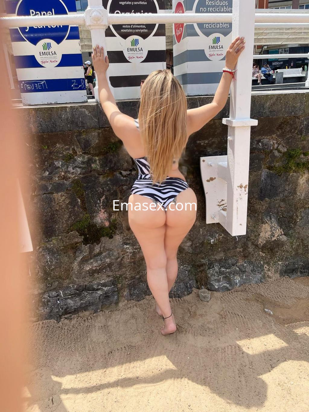 Puta con cabello largo y lacio, usando un traje de baño a rayas, posando en la playa de Oviedo.