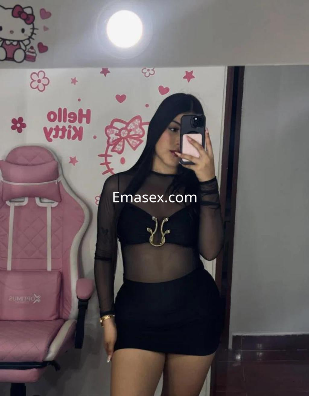 La puta posa en un espejo, luciendo un top negro transparente y una falda corta, con un fondo de Hello Kitty en Tenerife.