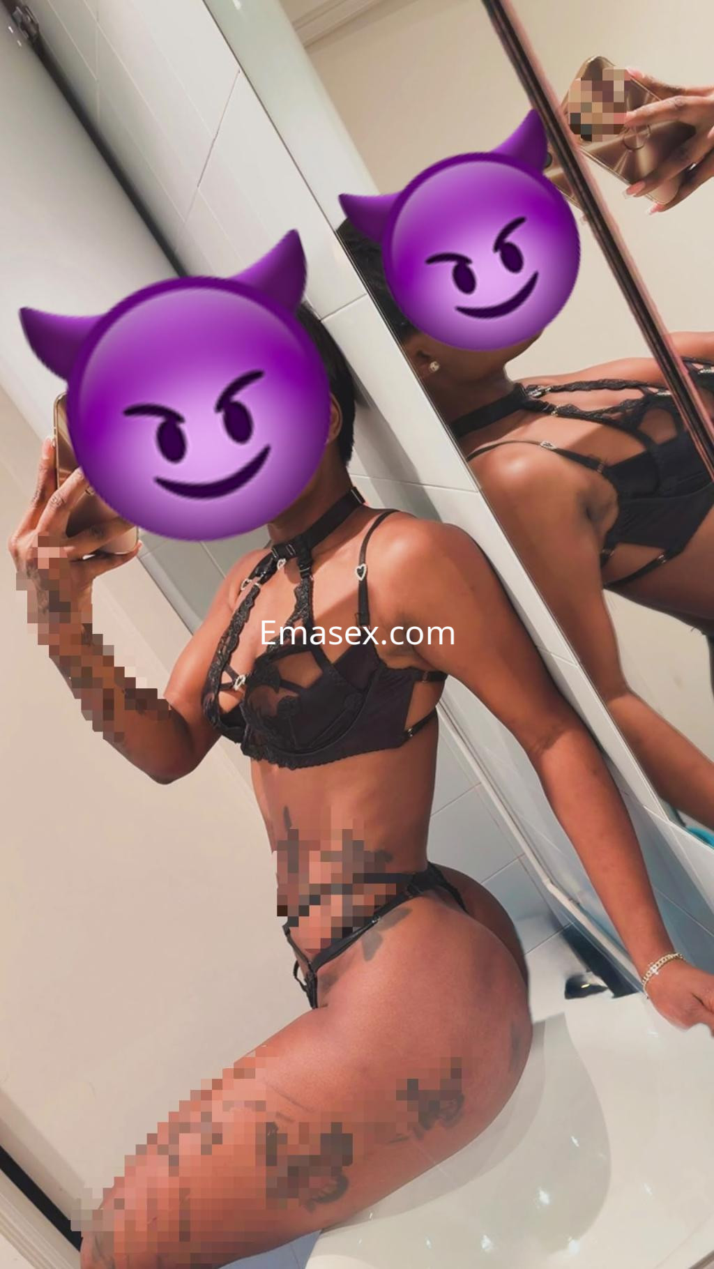 Escort en Bilbao luciendo un conjunto de lencería negra, posando de lado frente a un espejo en un ambiente moderno.