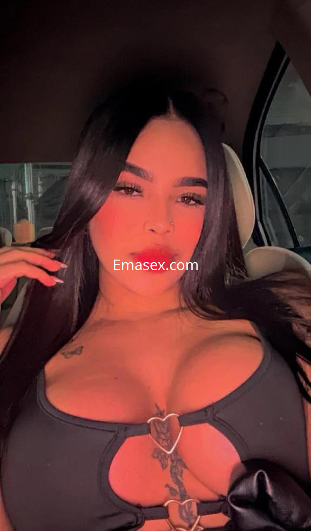Escort en Madrid con cabello largo y lacio, luciendo un top negro con detalles en el escote y labios rojos.