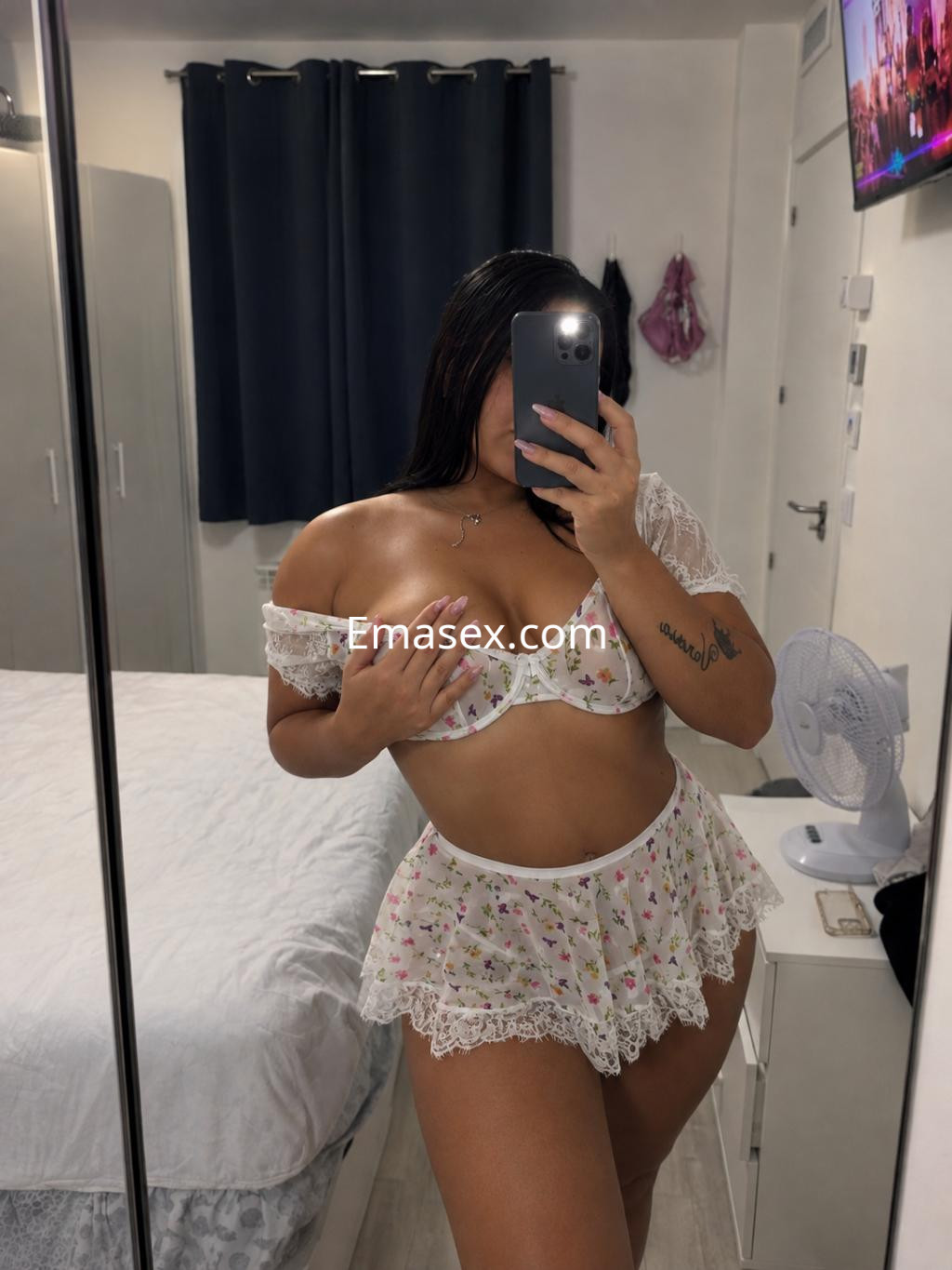 Escort en Córdoba, posando frente al espejo con un conjunto de lencería floral y detalles de encaje blanco.