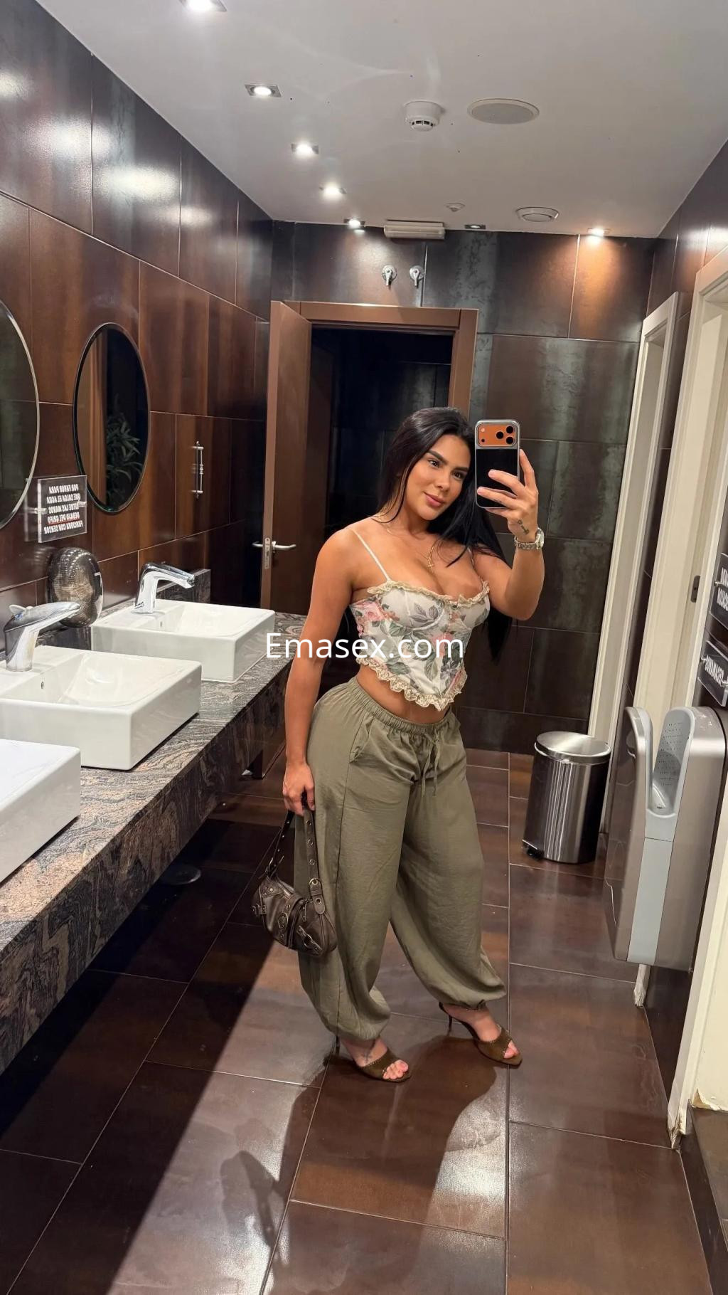 Escort en Palma de Mallorca luciendo un top floral y pantalones holgados en un baño moderno.