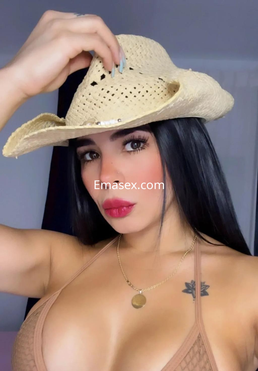 Escort en Murcia con cabello largo y oscuro, usando un sombrero de paja y un top marrón que resalta su figura.