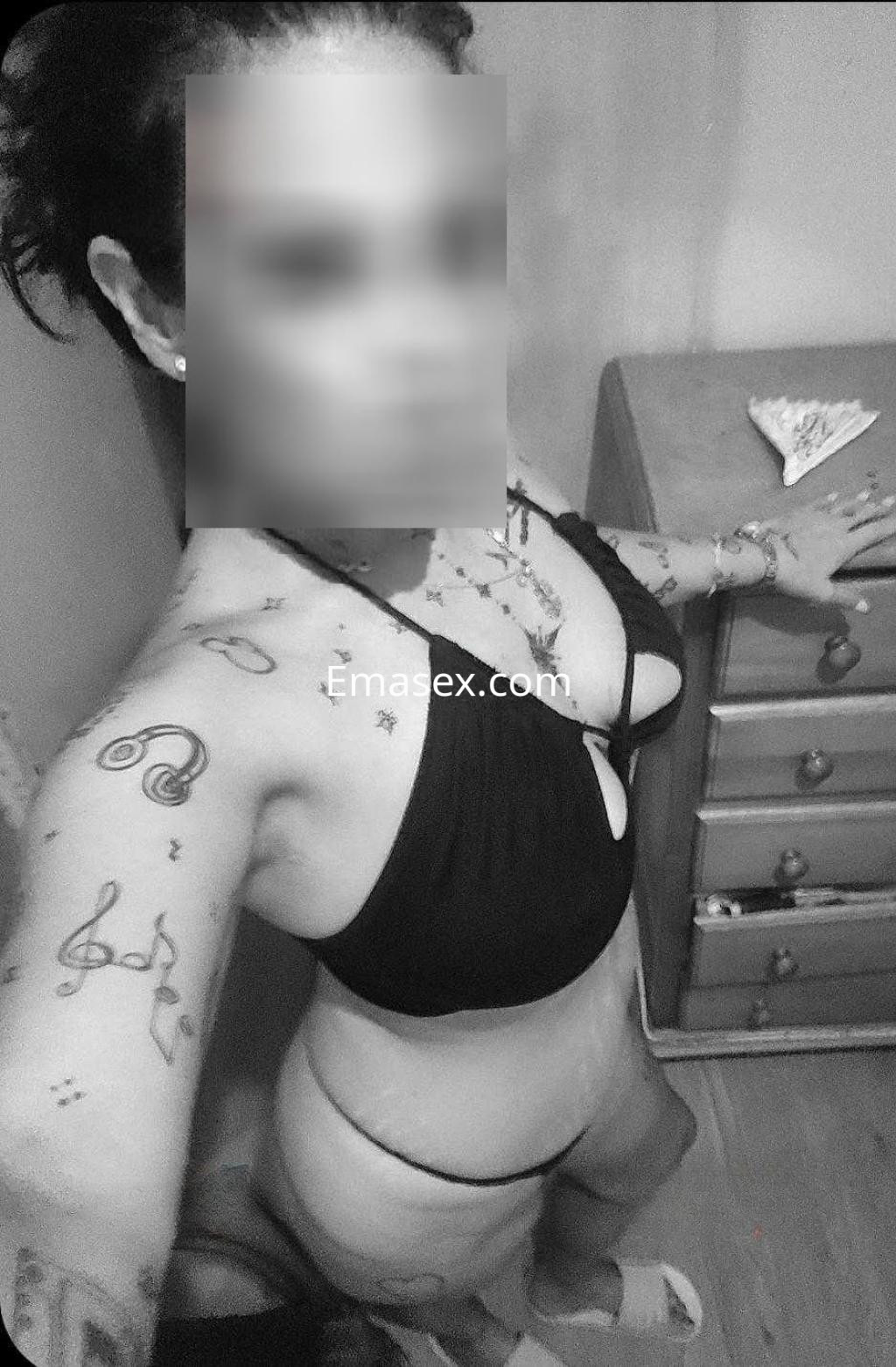 La puta posa en un bikini negro, mostrando sus tatuajes en un ambiente interior de Huelva.