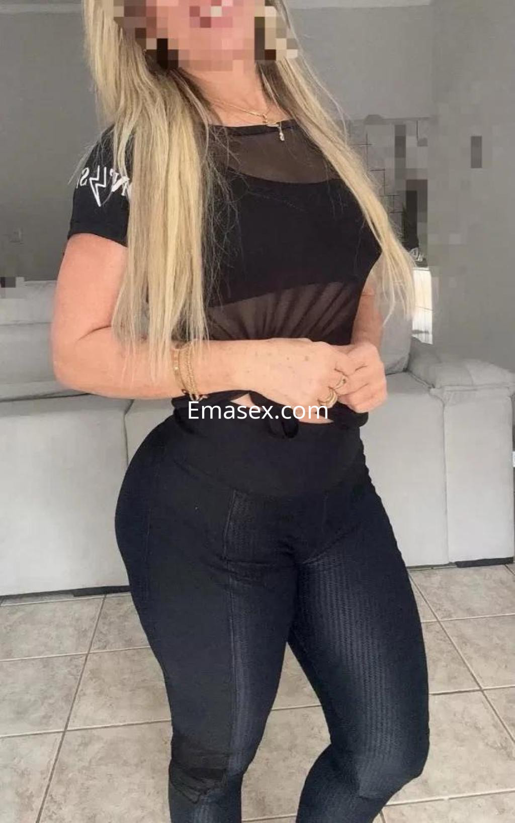 Puta en León, vistiendo un top negro transparente y leggings ajustados, posando con una actitud segura.