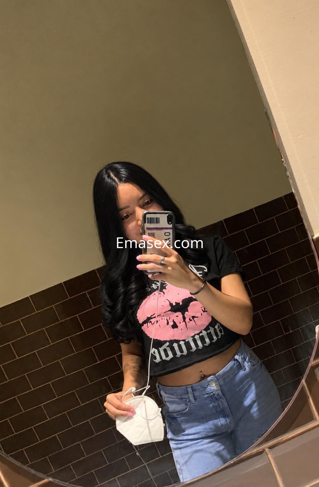 Puta en Santander, posando en un espejo con una camiseta negra y jeans, mostrando una imagen moderna y desenfadada.