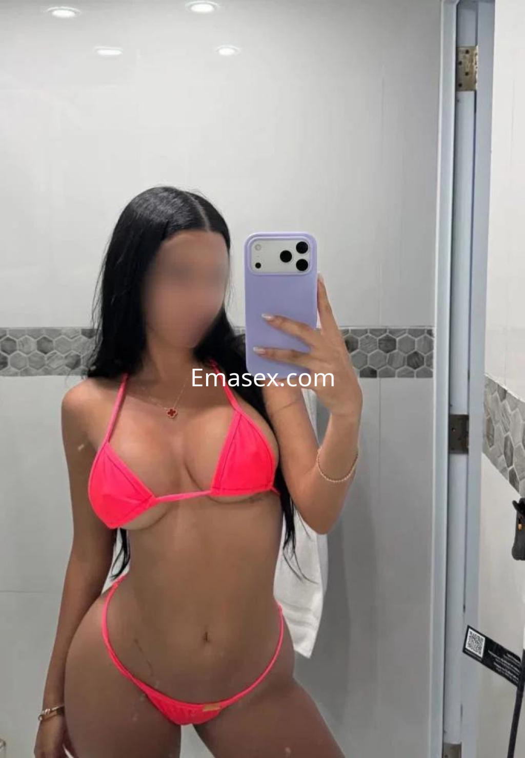Puta en Tenerife luciendo un bikini rosa brillante, posando frente al espejo en un baño moderno.