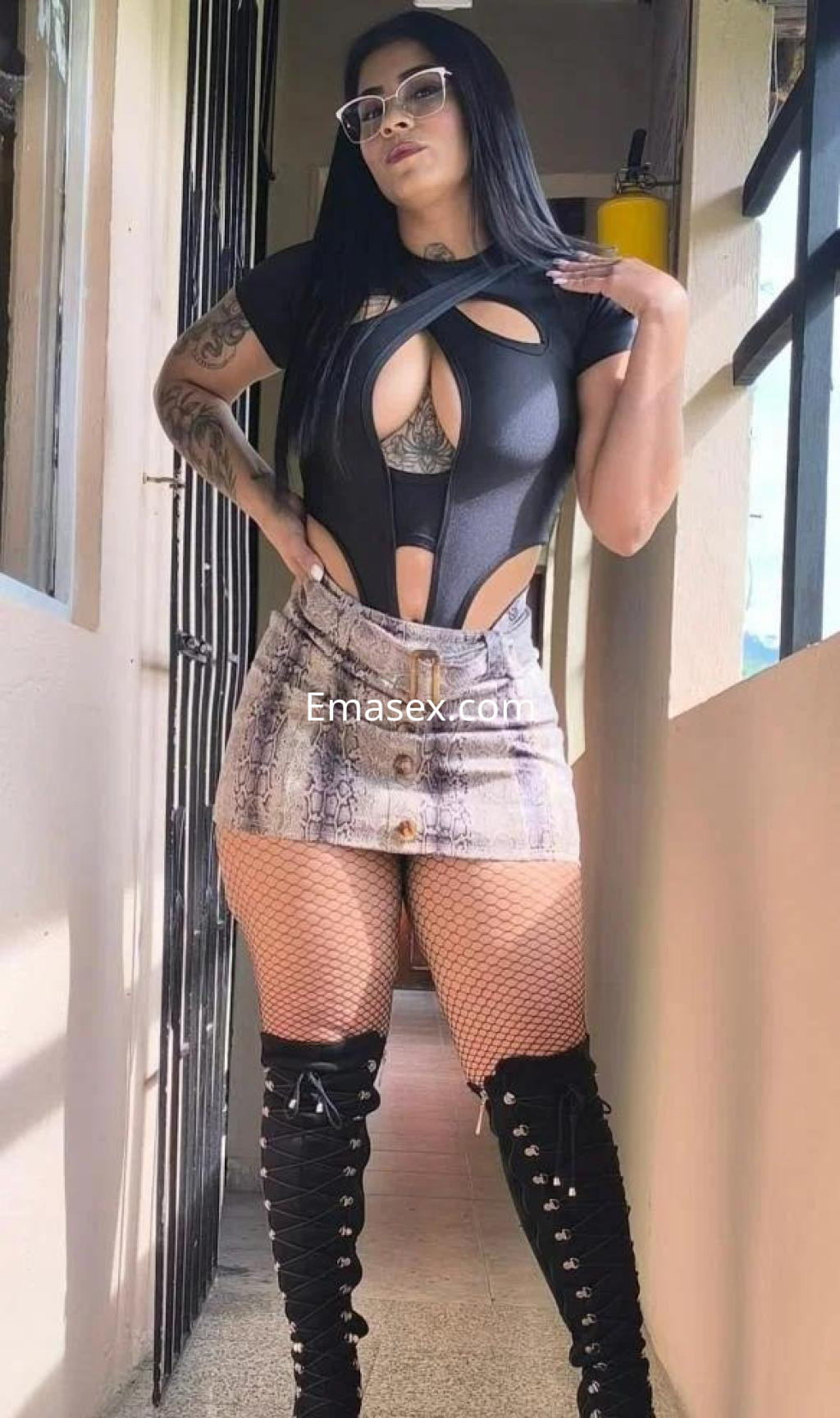 Escort en Barcelona con un body negro ajustado y una falda corta con estampado de serpiente, luciendo gafas de sol.