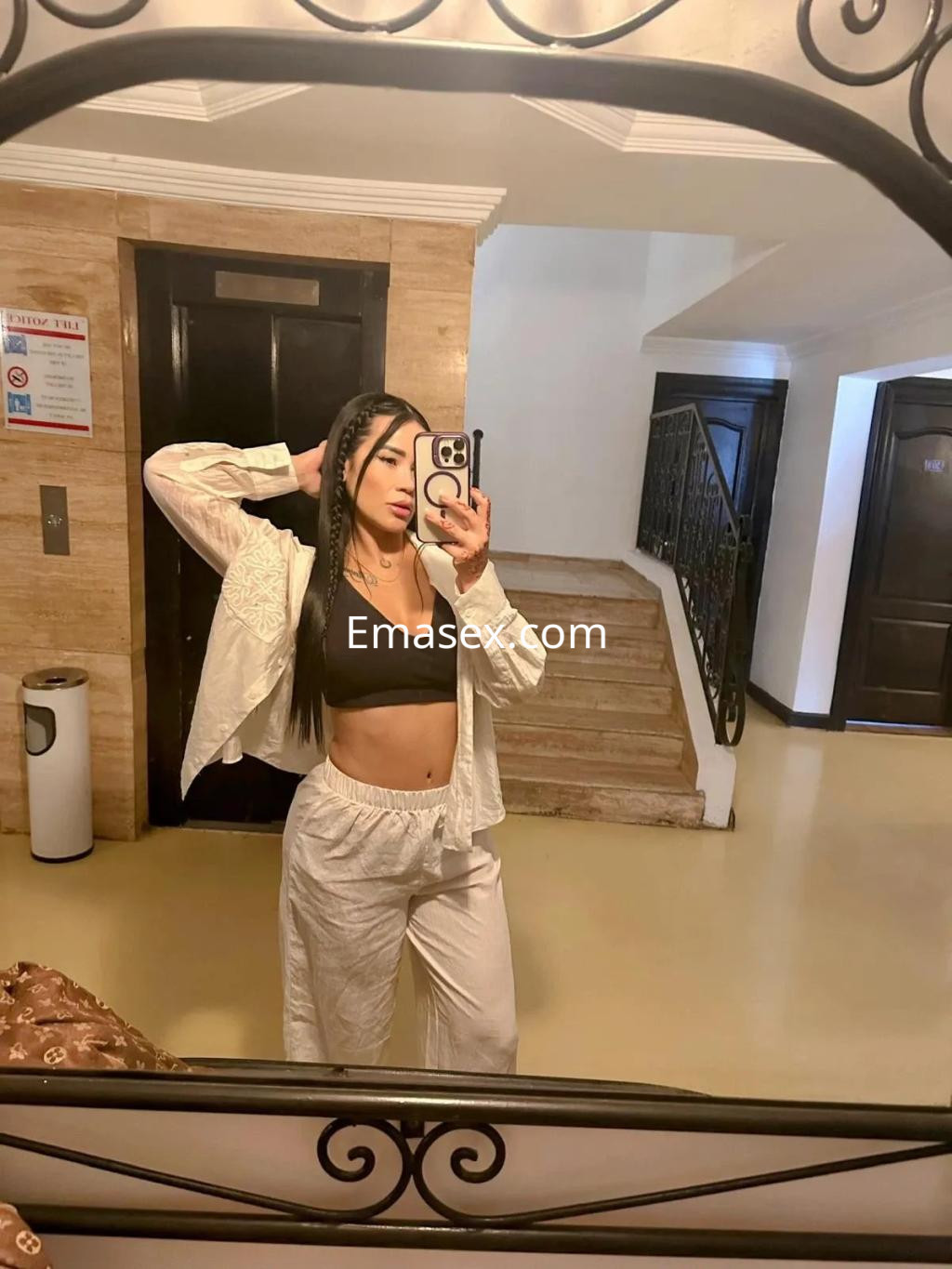 Escort en Valladolid posando frente al espejo con un conjunto blanco y top negro, mostrando un estilo casual.