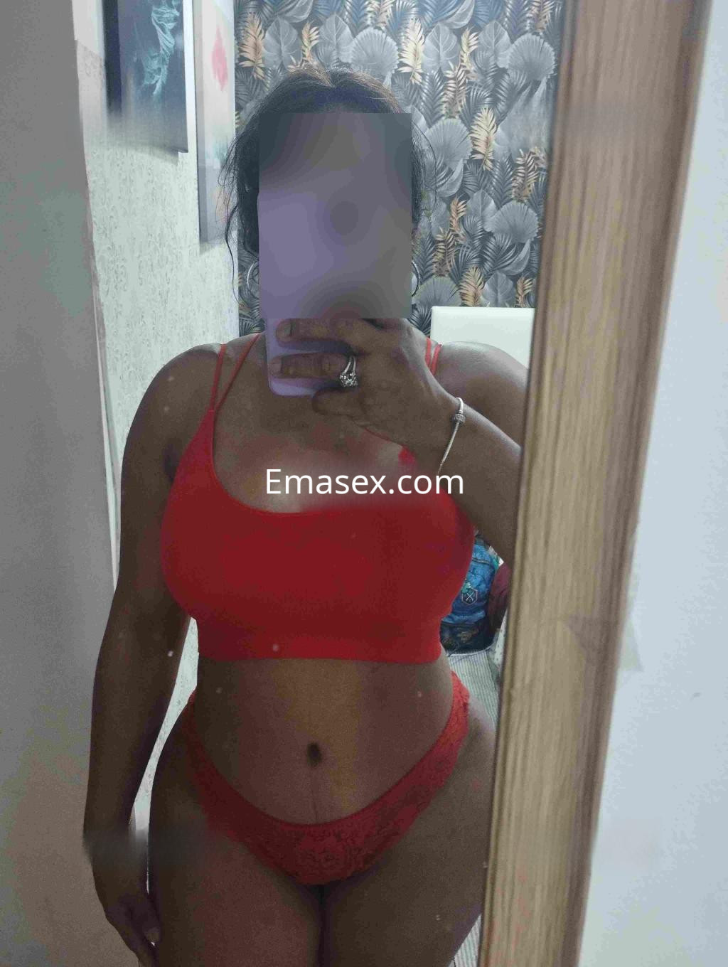 Puta en Zaragoza luciendo un conjunto de lencería rojo que realza su figura, con cabello oscuro y pose seductora.