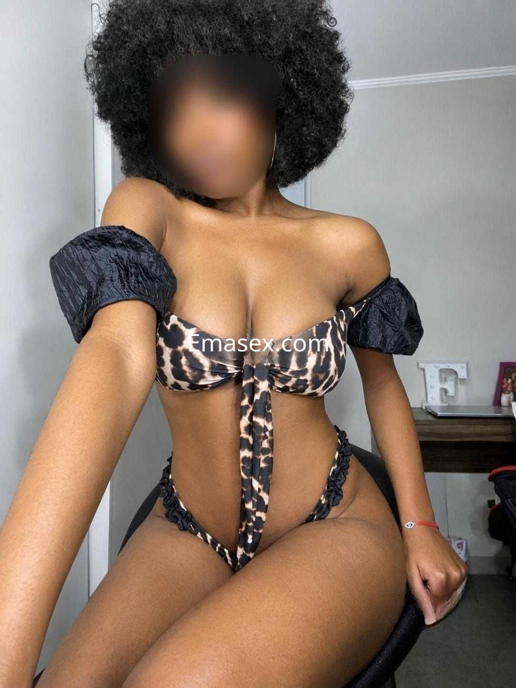 Puta en Tenerife posa con un bikini de estampado animal, mostrando su figura y cabello rizado.