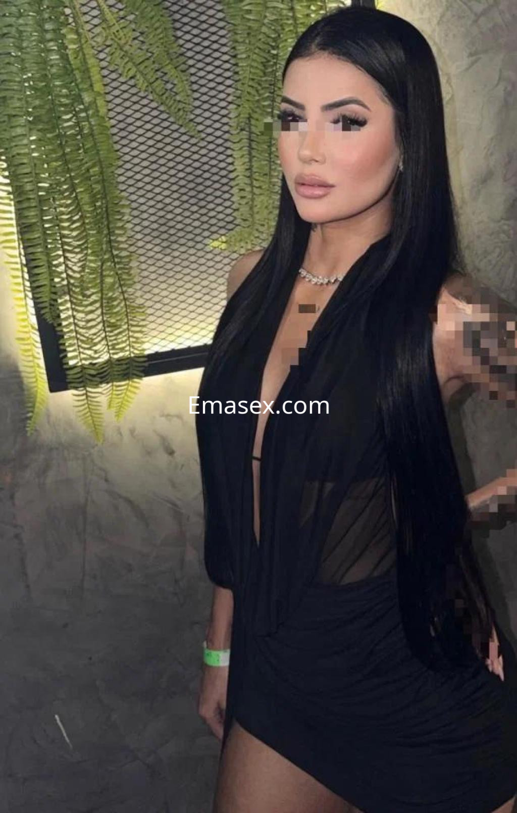 Escort en Cáceres con cabello largo y lacio, vistiendo un vestido negro transparente y elegante en un ambiente moderno.