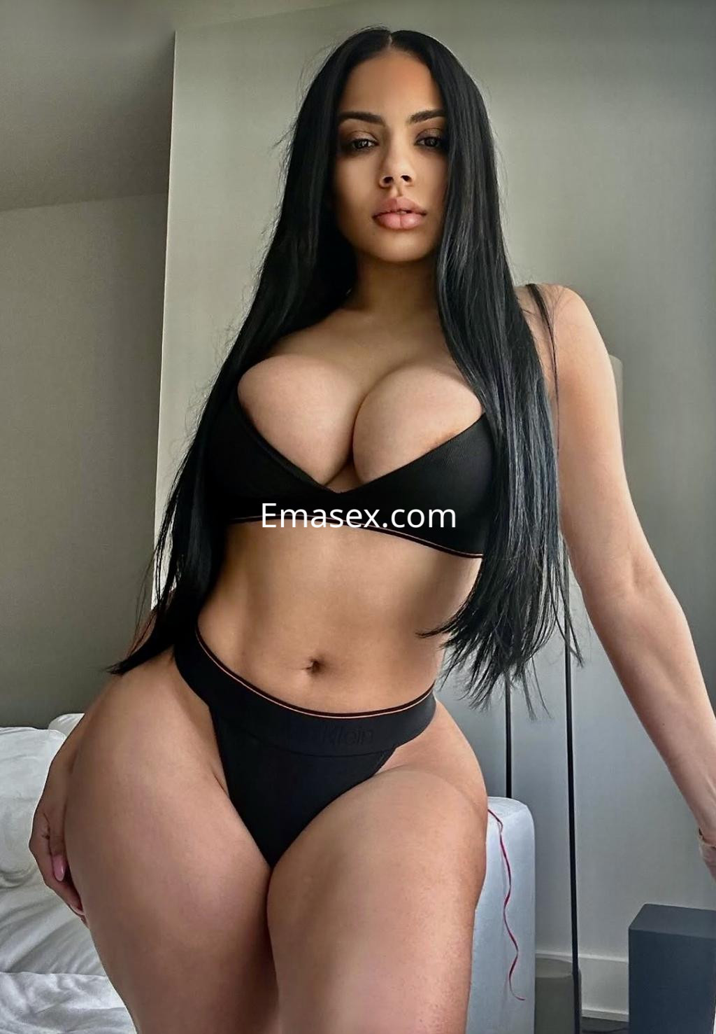 Escort en Valladolid con cabello largo y oscuro, vistiendo lencería negra ajustada que resalta su figura.