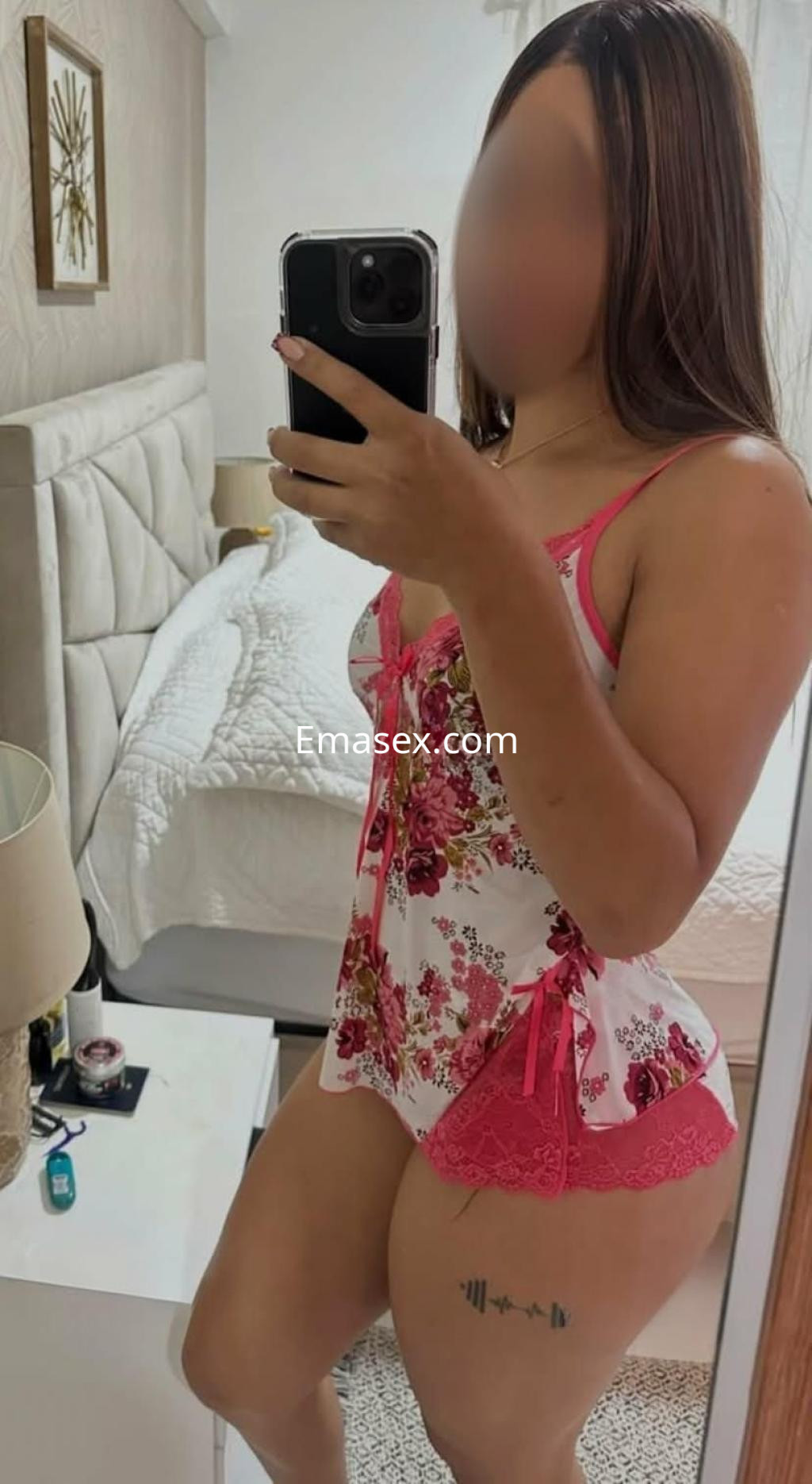 La puta en Granada se muestra con un conjunto de lencería floral en un espejo, destacando su figura.