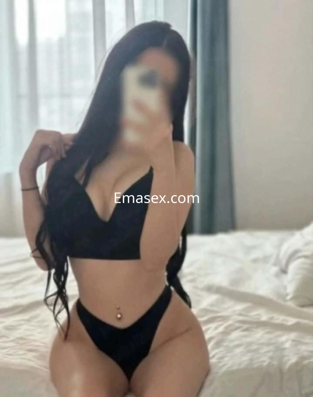 Escort en Almería posando en una cama, con un conjunto de lencería negra que destaca su figura.
