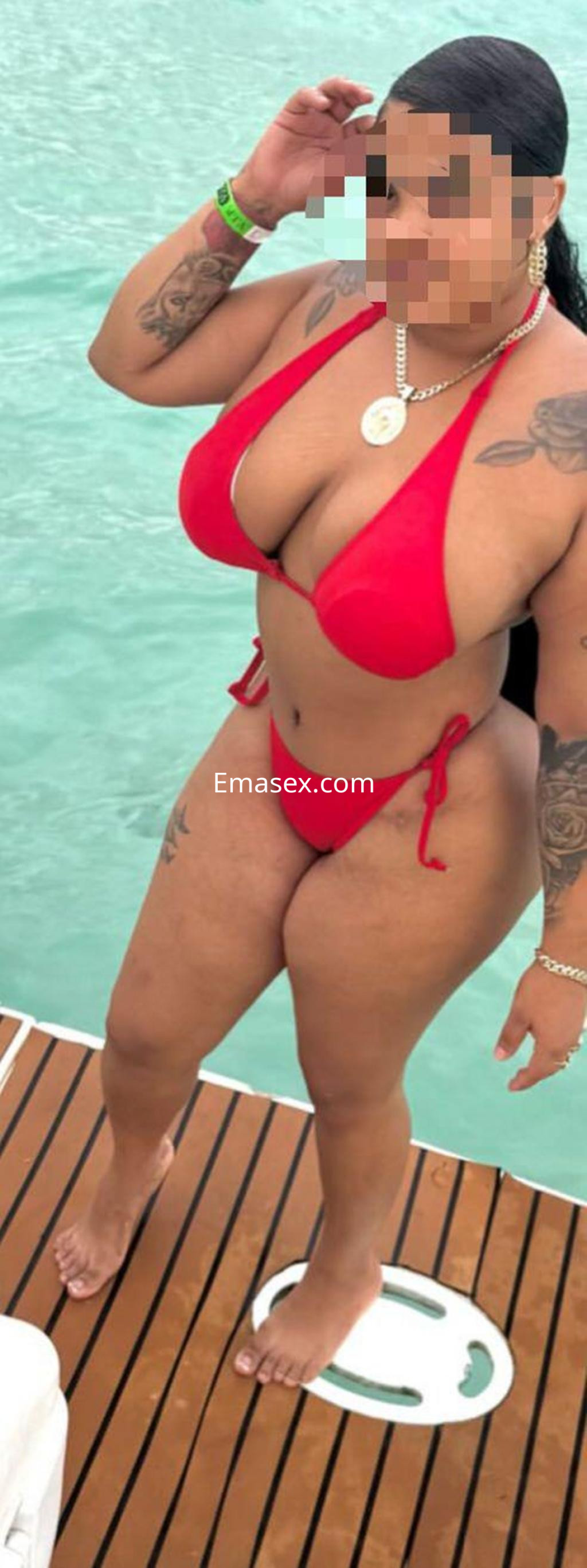Puta en Gijón con cabello largo y oscuro, vistiendo un bikini rojo, posando en un entorno al aire libre cerca del agua.
