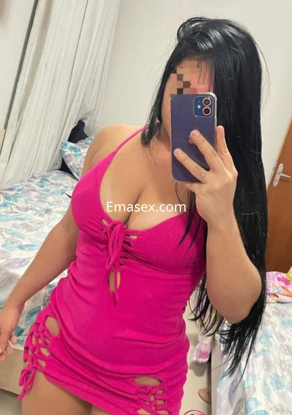 Escort en Madrid con vestido rosa ajustado y detalles recortados, posando frente a un espejo en un dormitorio.